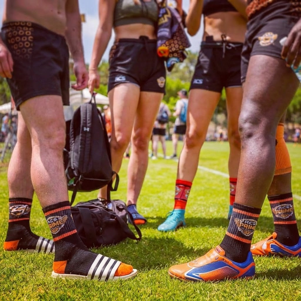 People wearing sports attire and socks on a grassy field